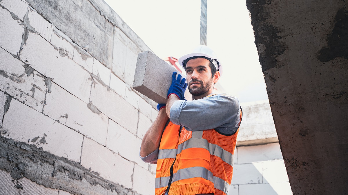  Builder wearing construction gloves and carrying a block