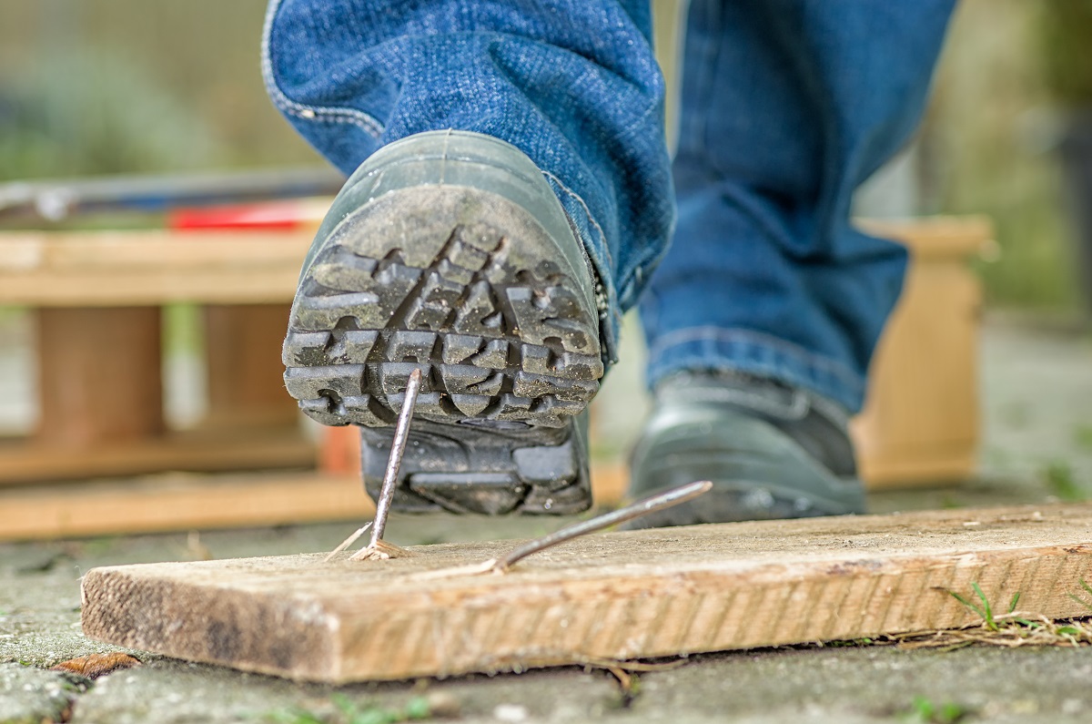A construction worker stepping on a nail